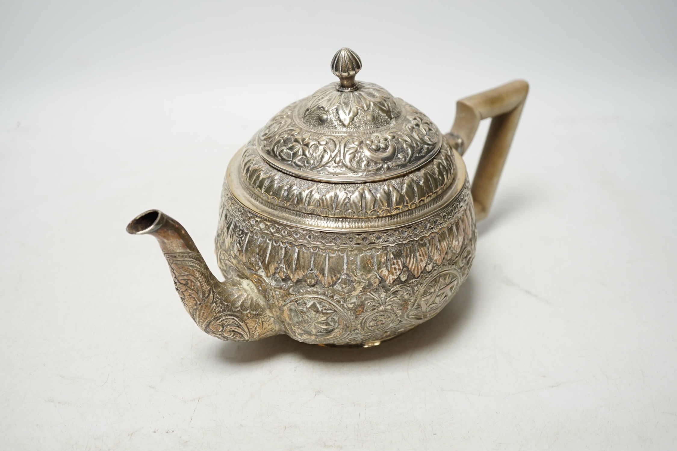 An Indian silver metal teapot with embossed and chased decoration, gross weight 16.9oz. Condition - poor to fair